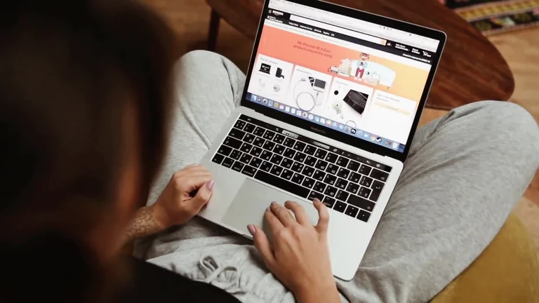 Person sitting on the floor with a laptop on their lap browsing a website