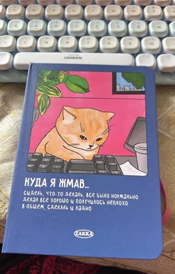 A blue notebook with a cartoon orange cat sitting at a computer keyboard on the cover, with Russian text.
