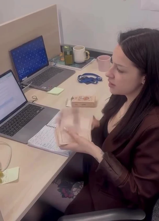 woman in office opening wallet at desk with laptop