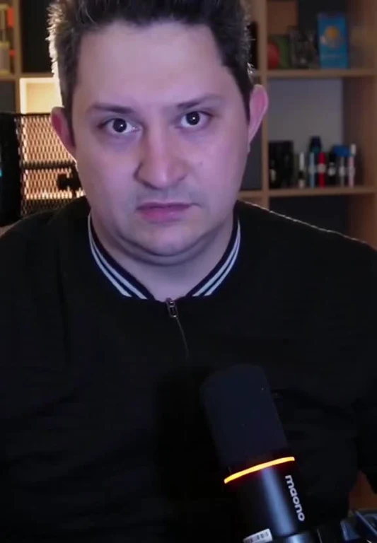 man with surprised expression sitting in front of a microphone