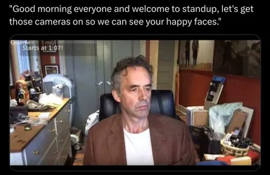man in brown jacket on video call with messy office background