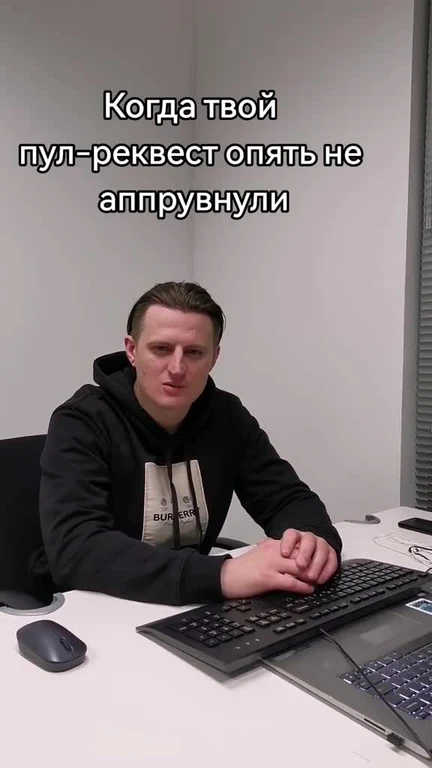 disappointed young programmer sitting at desk with keyboard and mouse