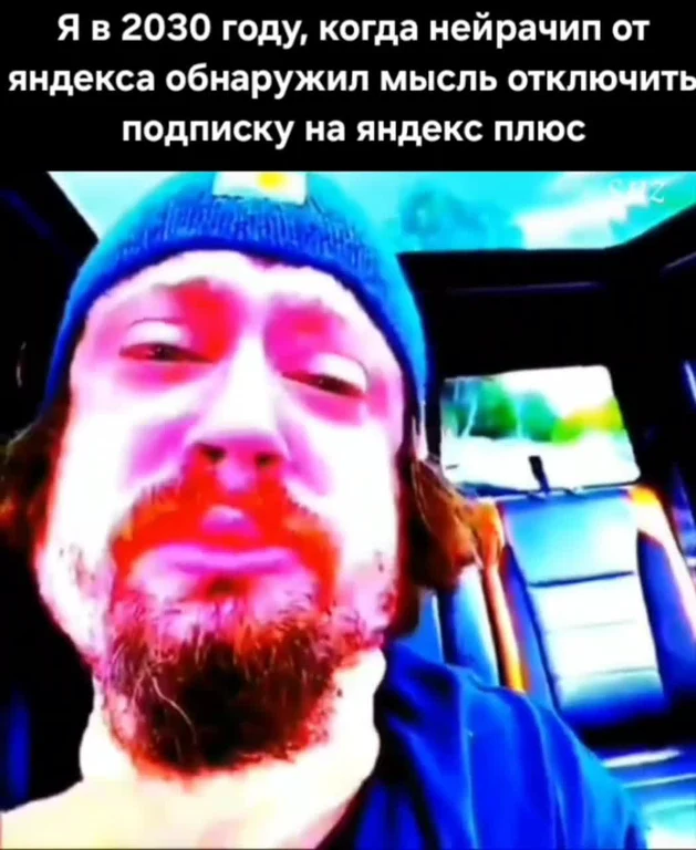 Искажённое лицо бородатого мужчины в шапке в машине с подписью про нейрочип Яндекса в 2030 году