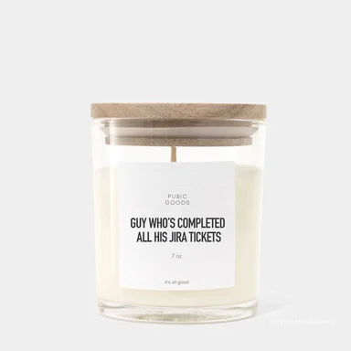 a candle in a glass jar with a wooden lid and a label that reads 'GUY WHO'S COMPLETED ALL HIS JIRA TICKETS'
