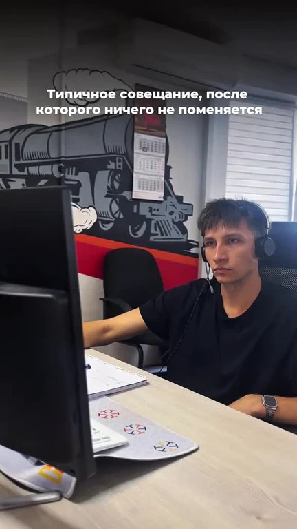 Man in headset sitting at desk with computer, looking unimpressed