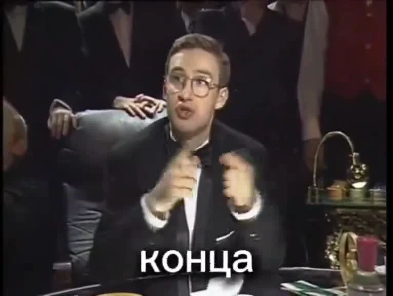 Man in a tuxedo and glasses shouting the Russian word 'konca' (the end) at a table