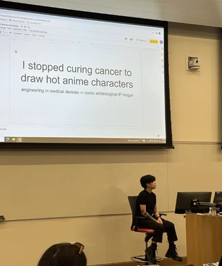 a woman sits in front of a projector screen with a humorous message about quitting medical device engineering to draw anime characters