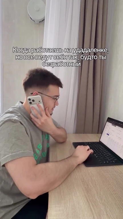Man sitting at a desk with laptop and phone, looking stressed while working remotely