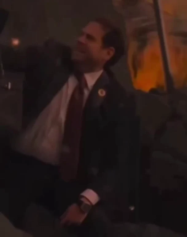 Man in a suit with a shocked expression looking at something in a dark room
