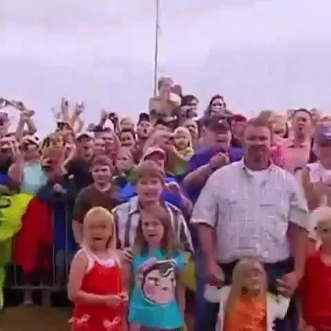 A large group of people and children looking up with shocked expressions and open mouths.