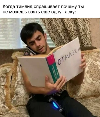 a man sitting on a couch holding a book with 'отмазки' written on it
