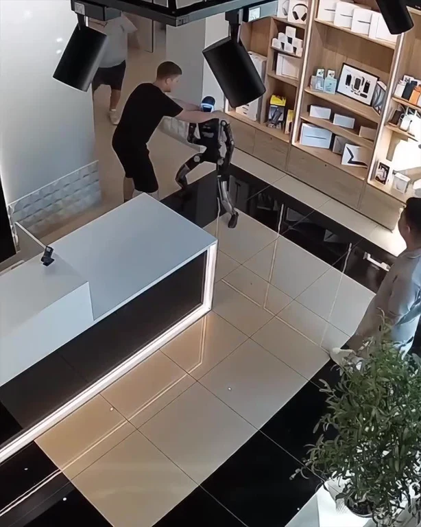 Humanoid robot in a tech showroom being physically confronted by a person, used as a visual pun about AI agents