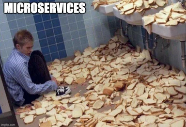 Man sitting on the floor of a tiled bathroom surrounded by hundreds of bread slices with the text MICROSERVICES above him.