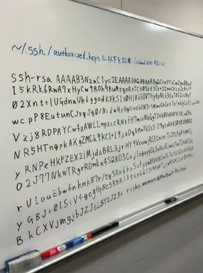 A whiteboard with a long SSH RSA public key and configuration instructions written by hand in black and blue markers.