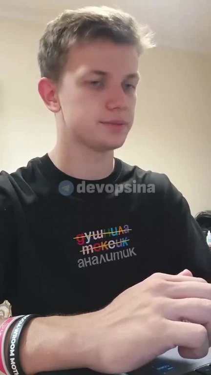 a young man in a black t-shirt with russian text looks unimpressed