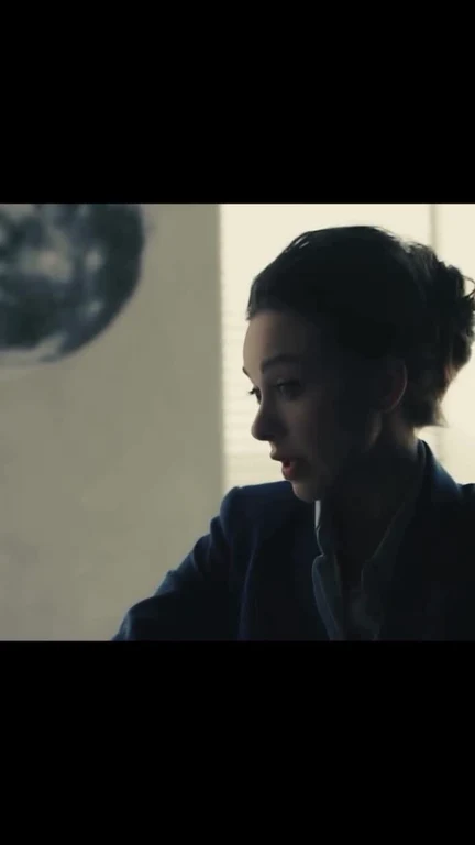 woman in blue jacket looking at globe on wall