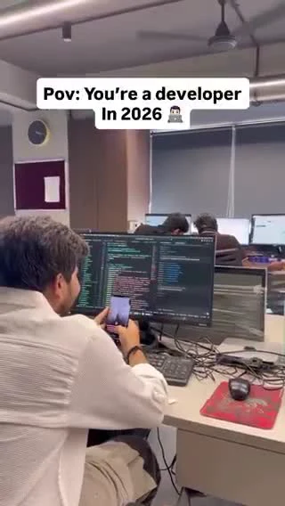 A developer in 2026 sitting at a desk with multiple computer monitors