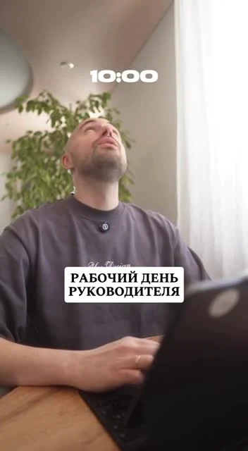 Man sitting at a desk with laptop, looking up with a relaxed expression, text overlay in Russian