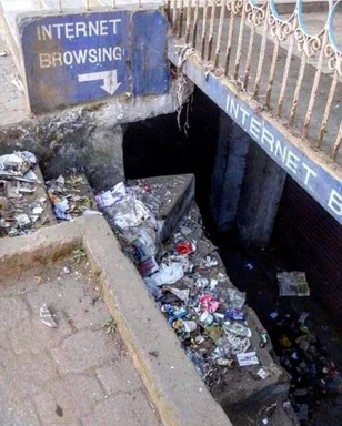 Dirty drainage tunnel with sign pointing to internet browsing