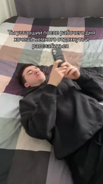 a young man lying on a bed holding a phone