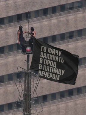 Masked figures hanging a black banner with Russian text 'Going to deploy a feature to production on Friday evening' on a building roof.