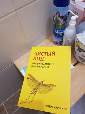 A yellow book titled 'Чистый код' by Robert Martin on a bathroom counter