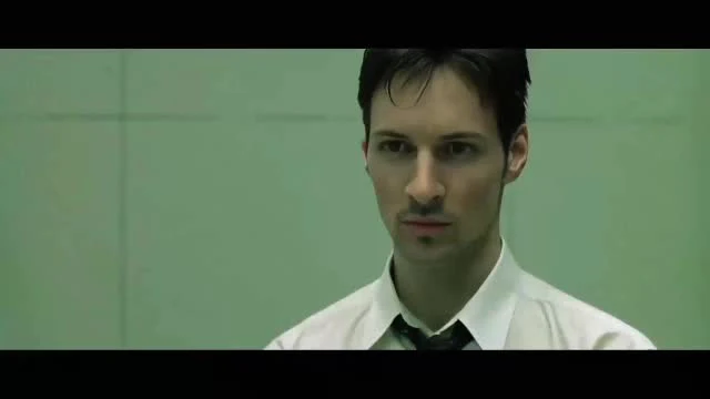 Close-up of a man in a white shirt and tie with a serious expression