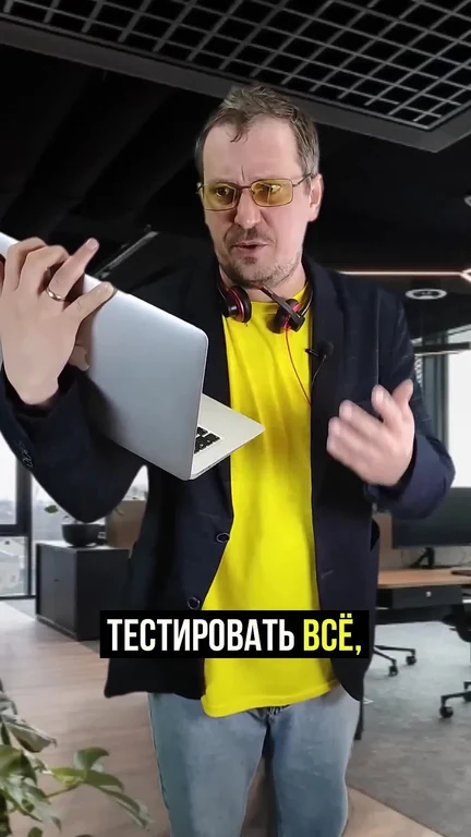 man in yellow shirt holding laptop in office
