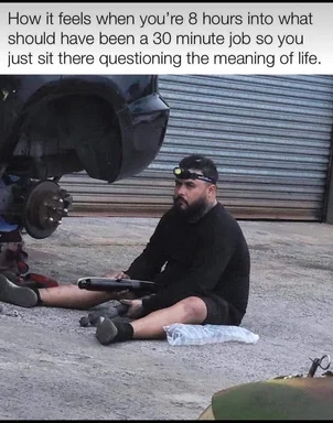 man sitting on ground under car questioning life