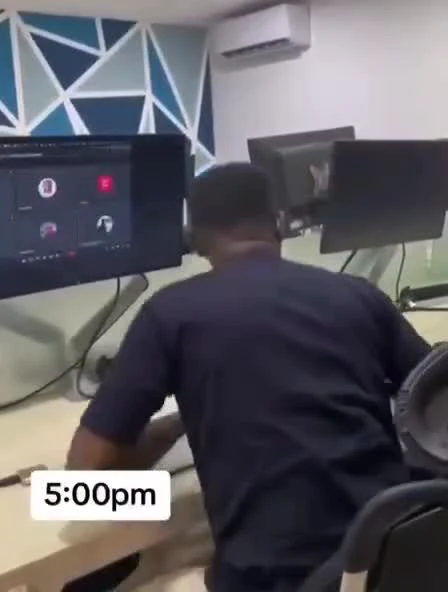 Man slumping over desk with multiple monitors at 5:00pm