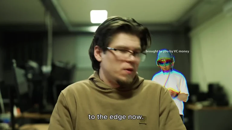 Man in brown hoodie with text 'to the edge now' and another man in the background with futuristic glasses and 'brought to you by VC money' text.