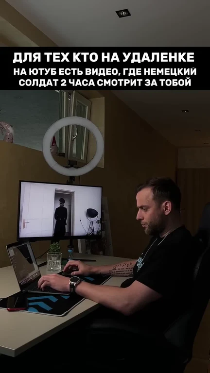 Man sitting at desk with laptop and monitor, looking concerned