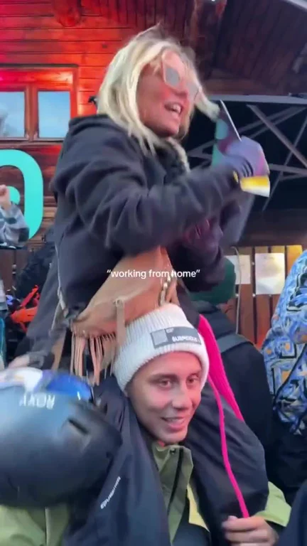 Man on ski lift with woman on his shoulders pretending to work