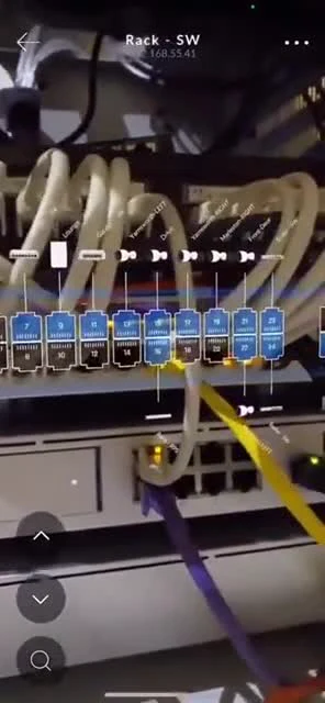 Close-up of a network switch in a server rack with labeled ethernet cables and port diagrams.