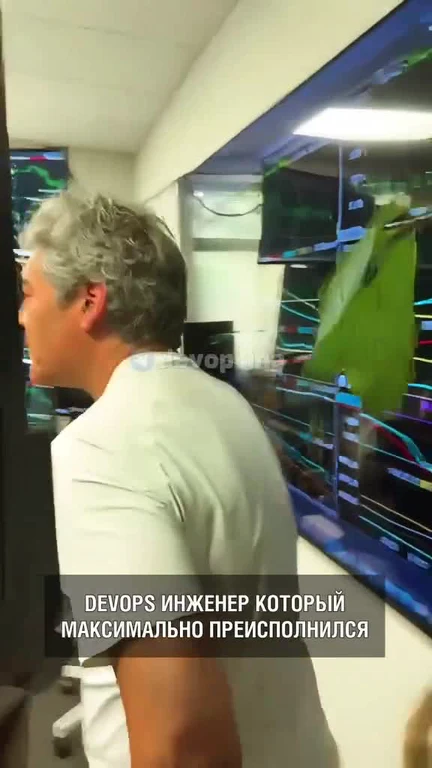 DevOps engineer with a thrilled expression standing in front of computer screens