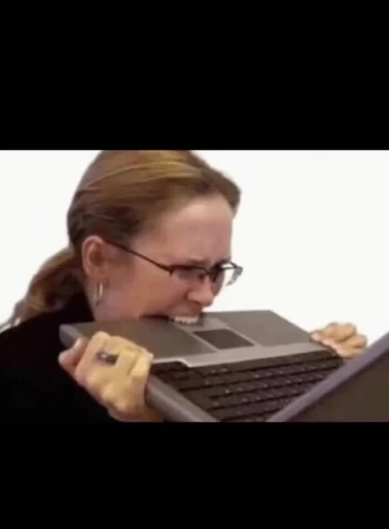 Woman biting a laptop keyboard in frustration