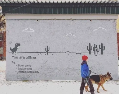 a child in a red hat and a dog walking past a grey wall with a dinosaur and cacti painted on it and text 'You are offline'