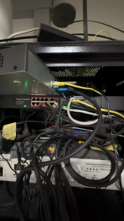 A chaotic tangle of black and yellow cables behind a power switch and server hardware.