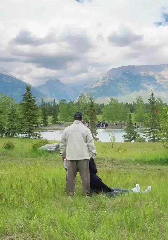 A developer relaxing in the grass by a lake with mountains in the background
