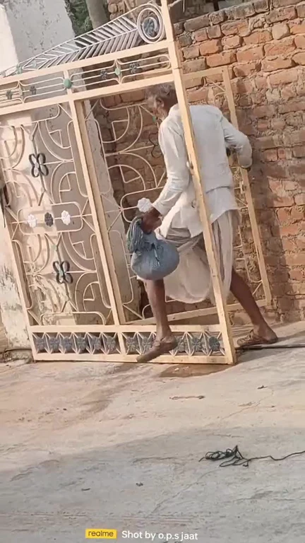 Man carrying a large metal gate frame to walk through the opening