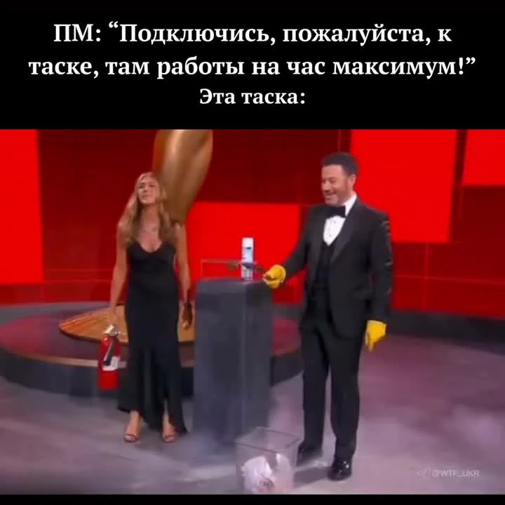 Скриншот из телевикторины: мужчина в смокинге и женщина в чёрном платье у пьедестала с маленьким предметом, подпись про ПМ и