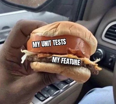a hand holding a burger with two layers labeled 'my unit tests' and 'my feature'