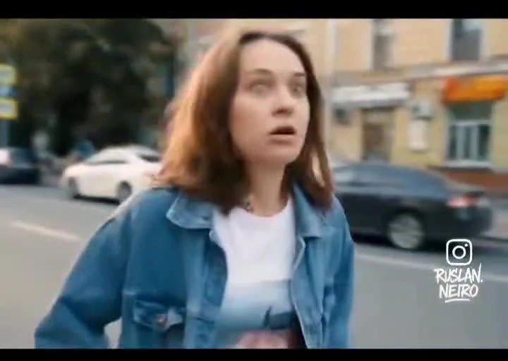 Woman in denim jacket looking shocked on city street