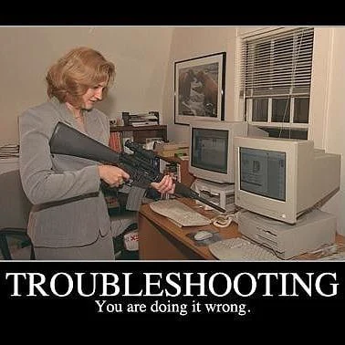Woman holding a large rifle pointing at computer screens on a desk with text 'TROUBLESHOOTING You are doing it wrong.'