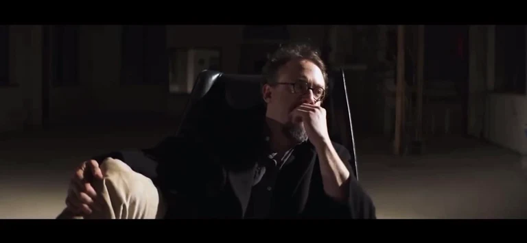 man sitting in a black office chair with his hand on his face
