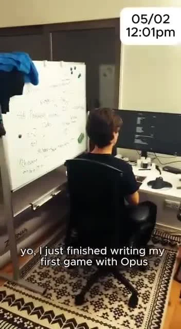 A developer sitting at a desk with a computer and whiteboard, celebrating writing their first game with Opus