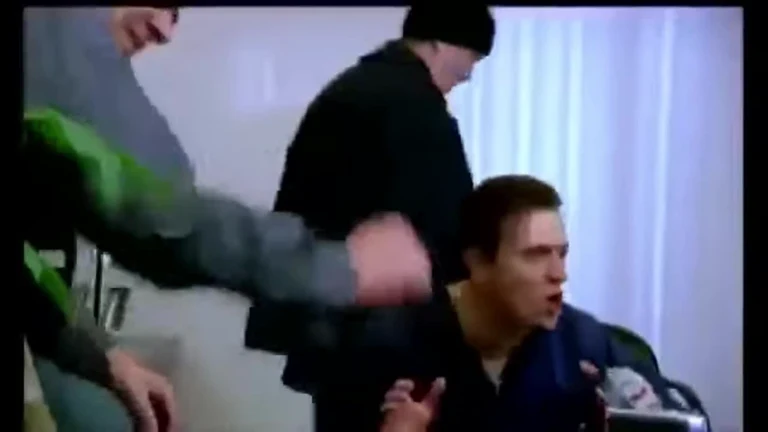 A man looking shocked and confused while being physically swarmed by other people in a room.