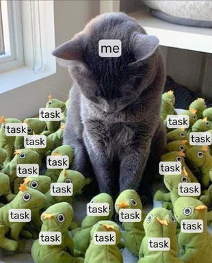 a gray cat surrounded by green frog toys with task labels, representing being overwhelmed by tasks