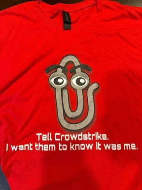 Paperclip with eyes and eyebrows on a red t-shirt with the text 'Tell Crowdstrike. I want them to know it was me.'