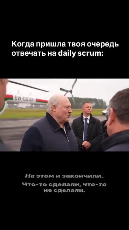 a man in a black jacket talking to another man with a helicopter in the background